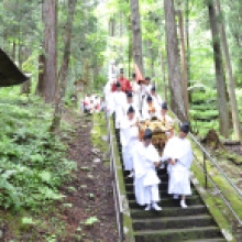 Carrying the portable shrine, dressed in priests' garb.