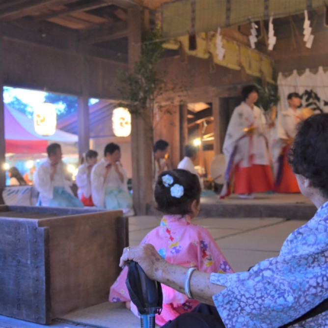 A senior and a village child watch the Maiko-mai dance